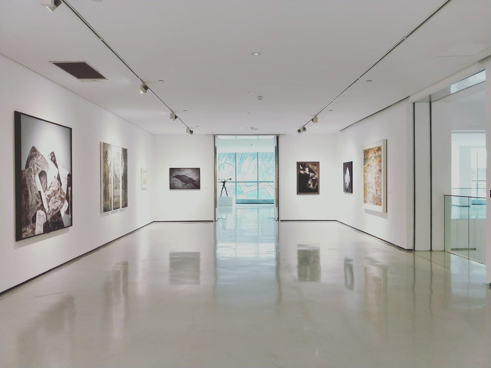 Framed paintings hung on a white gallery wall above a polished floor